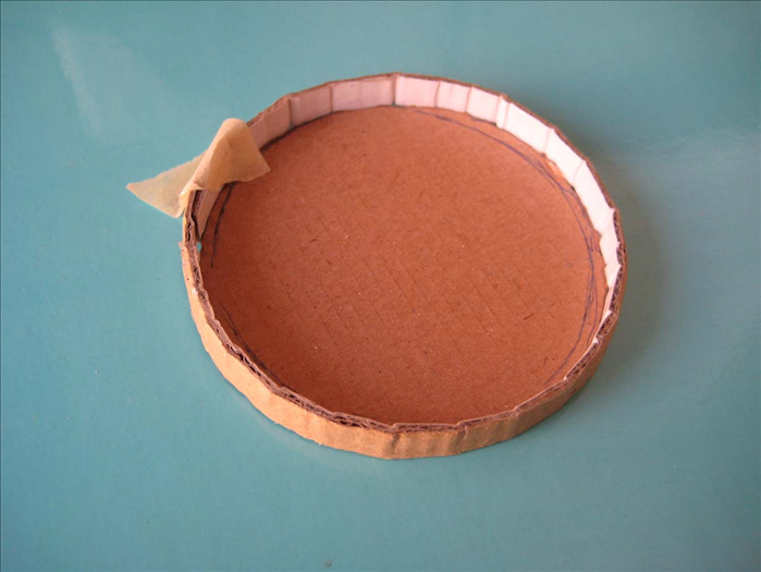 On a flat surface, align the strip around the circle with the glued area touching the outside of the circle.
Squeeze the overlapping edge tightly and put a piece of tape to hold it together while the glue dries.

Let it dry completely.
