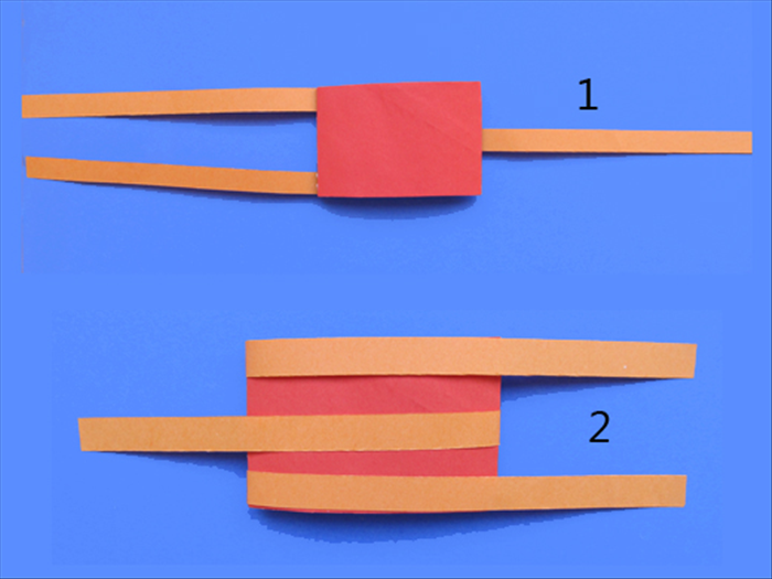 1.Take one of the rolls from step 8 and place it on the table with the strips side on the bottom.
2. Bring the strips up over the edge to the opposite side.
Do not glue it.

