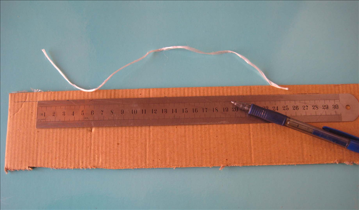 Use the length of the string for the  measurement of the length of a piece of corrugated cardboard .
This piece will be the rim of the cover. 

Decide the width of the rim you want for your cover and use that for the width of the piece you mark. The lines of the corrugated cardboard should be vertical.  

