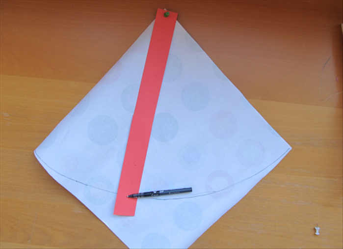 Place the square paper with the points at the top, bottom and side.

Push the pin at the top center of the strip and through the top point of the square paper.

Pierce a hole, with a pin or  the point of the pen, where it meets with the left point of the square paper.

Pivot the strip with the pen point in the hole to mark an arc.

Cut along the arc line
