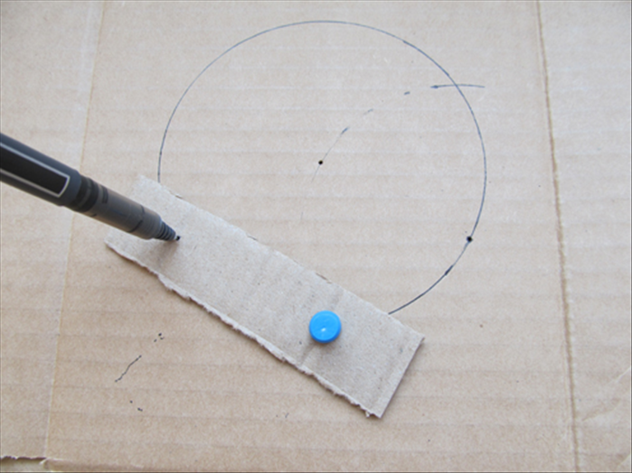 Put the pin through a hole in the strip and into the hole in the cardboard underneath
Put the point of the pen in the second hole, rotate the strip and make a mark where it comes to the circle
