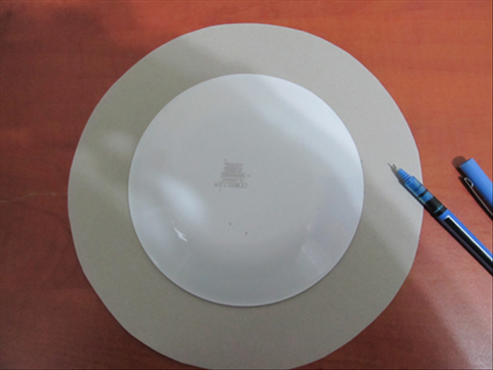 Put the small plate in the center of the large round  cardboard from step 2.
Trace the outline of the plate.