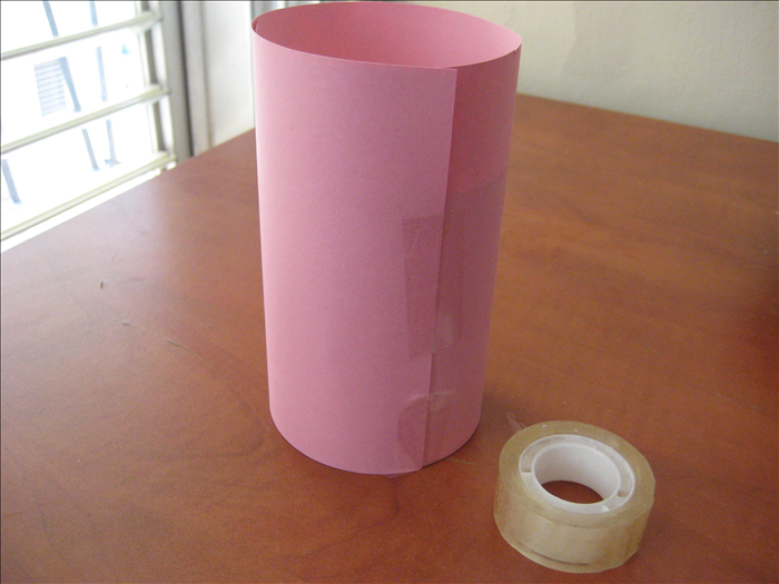 Roll the can in the paper. Stand it on its bottom, adjust the paper so that it aligns with the table and tape the paper closed.
