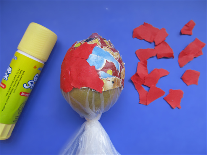 Cover the lemon with 2 more layers of scrap paper. Coat each layer with glue and smooth it out.
Cover it with a final layer of the color you want the bell to be.
