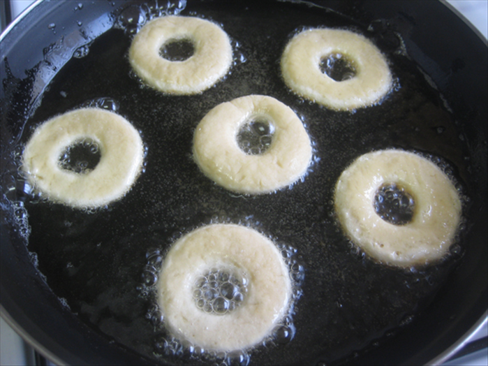 Fry in medium low heated oil until the bottoms are light brown. 
Test the heat on a hole to see if it is too hot.
They will fry fast but you do not want the oil so hot it burns before the inside is cooked or not hot enough that it gets soggy from being too long in the oil.
