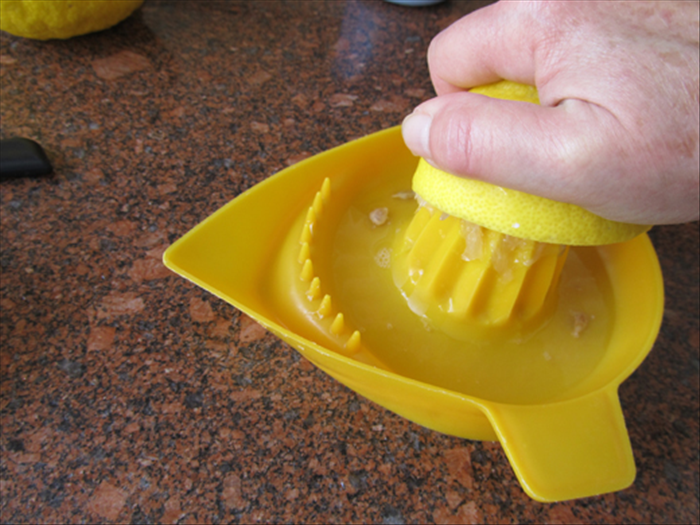 Press and rotate the cut end of the lemon on the juicer.