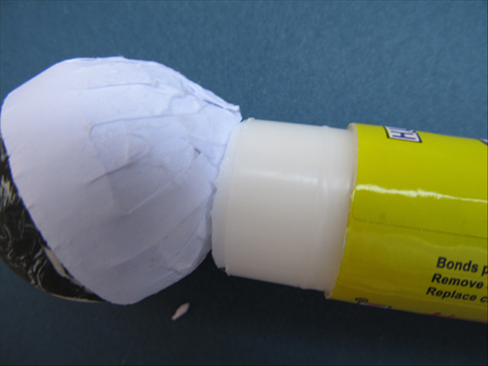 Continue to smear glue over the fringe and press it in place around the ball
Use your finger to smooth it more.