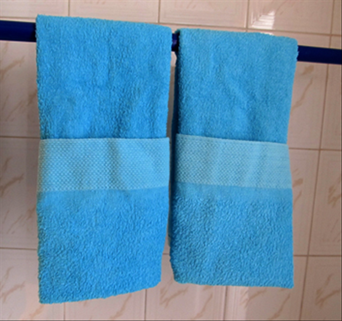 To hang the towel, the top is inserted behind the towel rack.