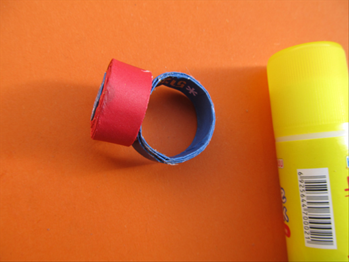 Put a generous amount of glue on the end of the ring and press the coil to it.