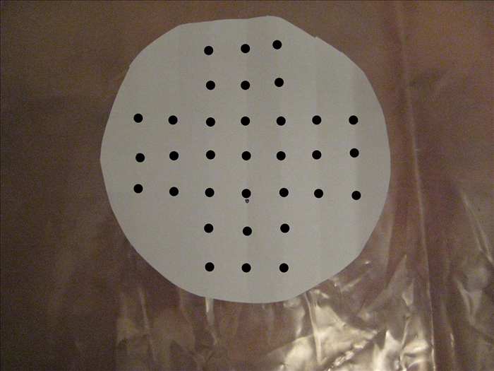 Use 2 piece of tape to hold the paper circle you just folded on top of the cardboard circles

Use the points where the creases meet as a guide
 Make a dot in the center with a dark pen or magic marker

Make 3 dots on both sides of the center dot
Make 3 dots above and below the center dot
Make a dot on both sides of the dots you just make – see picture for placement

It is important to pay attention where there are no dots
