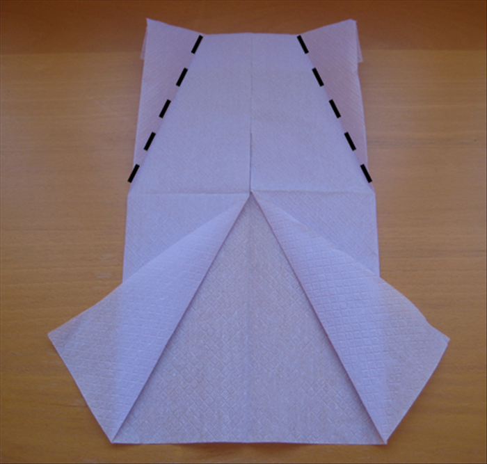 Flip the napkin over again.

Fold the top corners at an angle down to the center.

See the result in the next picture.
