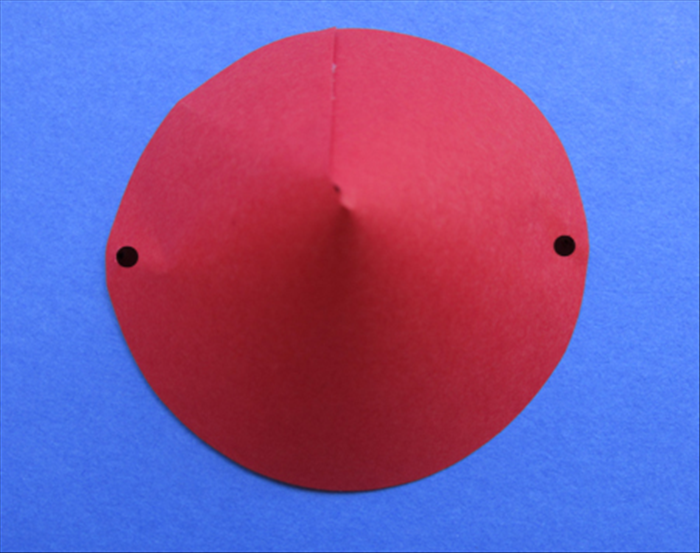 Place the overlapped edge at the top. 
Use a hole puncher or sharp pointed object to make 2 holes on both sides of the hat
