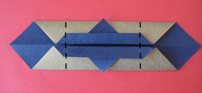 Fold both sides to the back where the straight edge of the little triangles end.