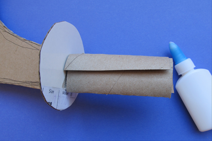 Coat the knife handle, on both sides with glue ( up to the circle)

Wrap the slit toilet paper roll around over the glue. 
Flatten it and put glue under the flap.