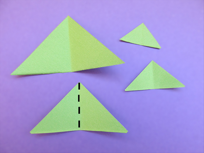 Take one triangle of each size.
Bring the bottom points together to fold them in half.
Crease and unfold
