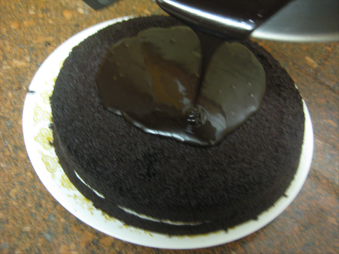 Pour the icing right away on top of the cake
Quickly before it cools too much spread it around  to cover the cake
