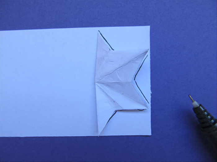 Place the half star on the edge of the paper strip as shown
Trace the outline of the points up to the fold
