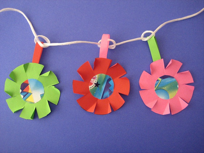 Materials:
Colorful scrap paper
drinking glass, coffee cup or similar circular object
bottle cap or similar small circular object
Scissors
Paper glue
Pen or pencil
String for hanging the garland
