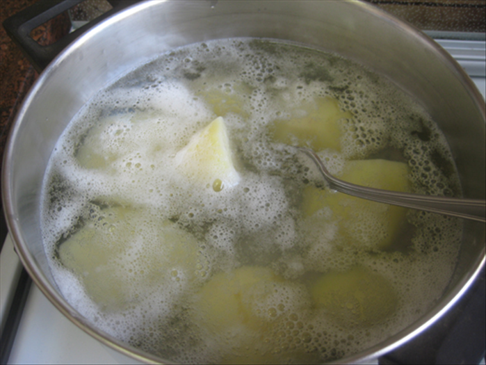 Peel the potatoes and cut them into halves.
Boil the potatoes in water until they are soft enough to pierce with a fork, not hard at all, but not cooked so much that they fall apart.
