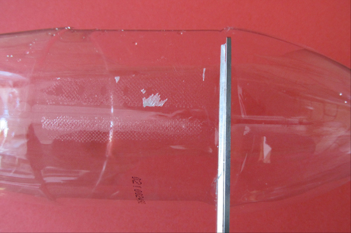 Remove the curved top of the plastic bottle by cutting where the straight edge begins