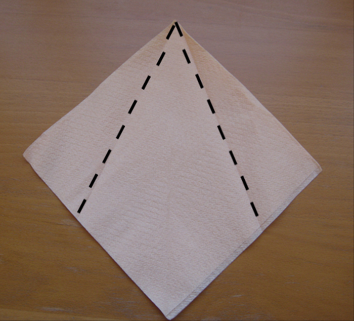 Use a paper napkin  as it comes folded in the  
package.
A cloth napkin needs to be fold it in half once horizontally and once vertically.

Place the napkin on the table with the open side on the bottom.

Fold the top sides down to align at the center.