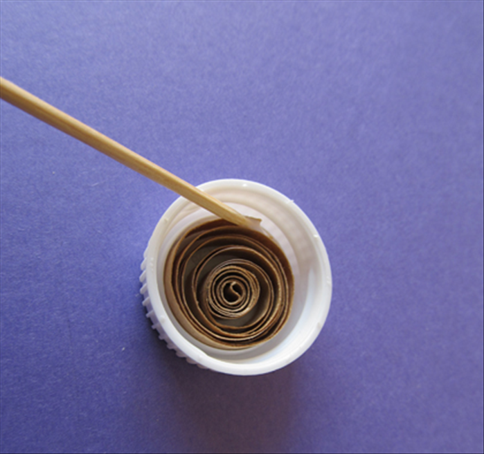 To make looser shapes:

Carefully remove the rolled up paper strip and put it into the bottle cap

Use the second toothpick to apply a tiny bit of glue to the end only

Let the glue dry

