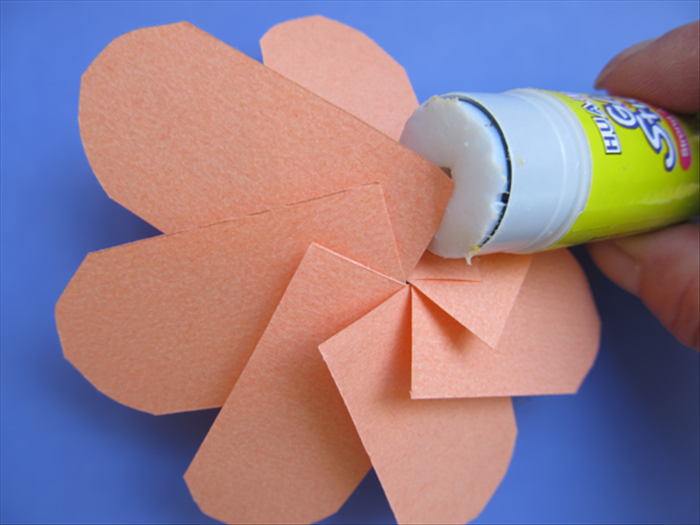 <p> Flip the flower over to the back side.</p> 
<p> Put glue on the edges sticking up and press them in place. You do not want to flatten the cone shape so stick a finger underneath to press against.</p> 
<p>  </p>