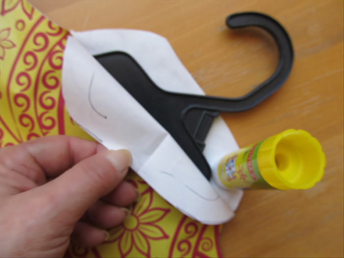 Slide the hanger up from the opening at the bottom. 
Bring the hook of the hanger through the unglued top. 

Glue the top closed on both sides of the hook.