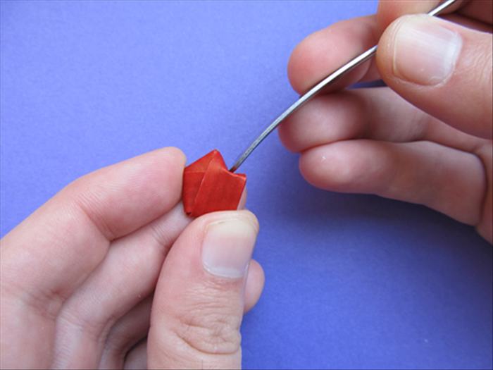 Hold the pentagon shape with your thumb at the flat bottom and your pointer finger at the point opposite it. Use the flat edge of a spoon or your finger nail to push in the side