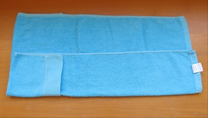 Flip the towel over to the back side.

Fold the bottom edge up one third of the way to the top.