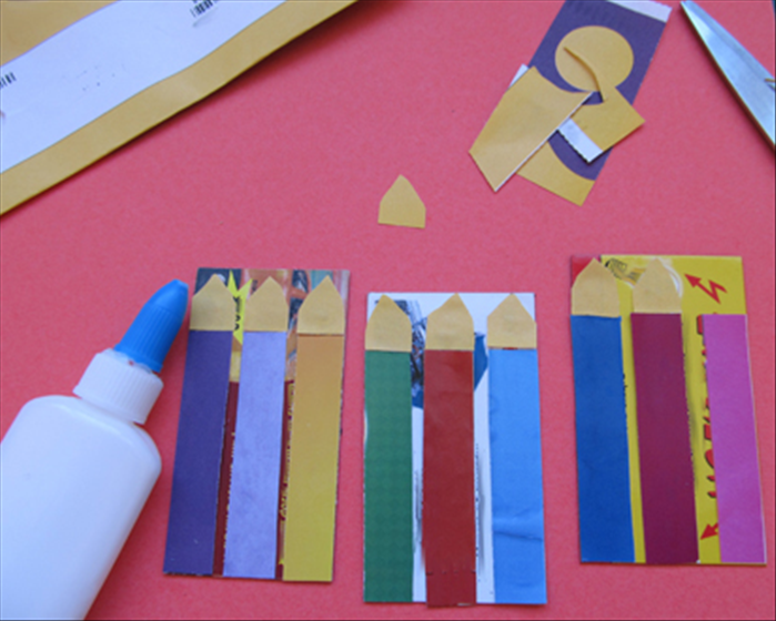 Glue the strips to the printed side of the magnets.
Cut out 9 yellow or orange fire shapes and glue them to the top of the strips.
Cut out the shapes of the candles * including the fire on top
