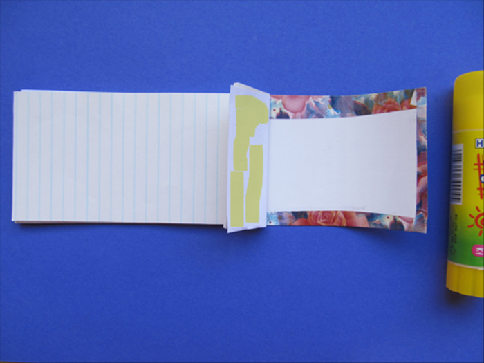 Align the note paper to the bottom of the junk mail paper - The edge that does not have the decorative paper. 
 Put glue on the folded area and press  it down in place.
