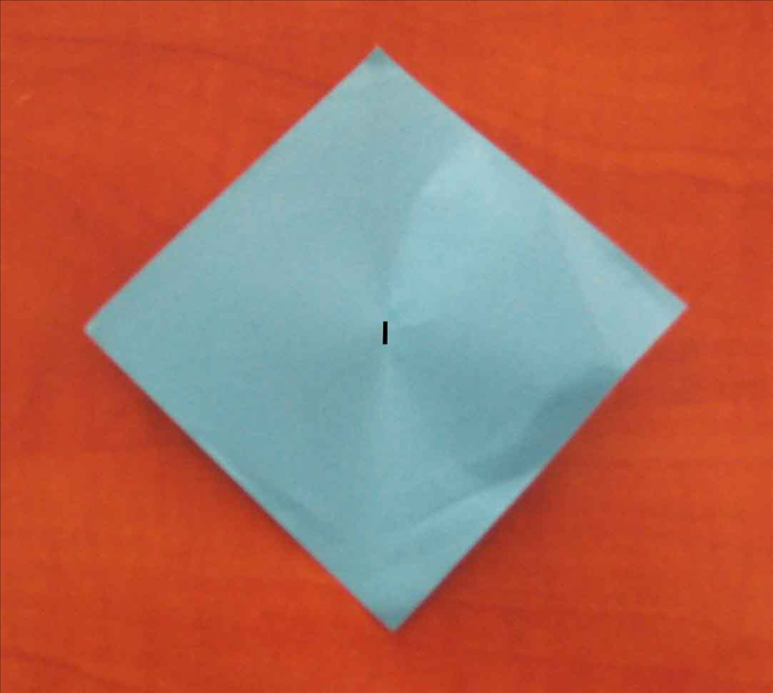 Place the square sheet of paper so that its points are at the top, bottom and sides.

Bring the right point to the left point as if you were going to fold it in half. Do not crease - only pinch it at  the center to make a mark.
Unfold
