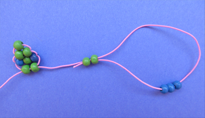 Bring the end of the same string around and through the right side of the 2 green beads.