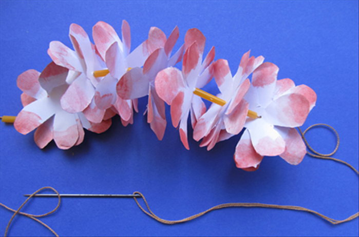 Continue stringing a straw and then a flower until you have the length you want.