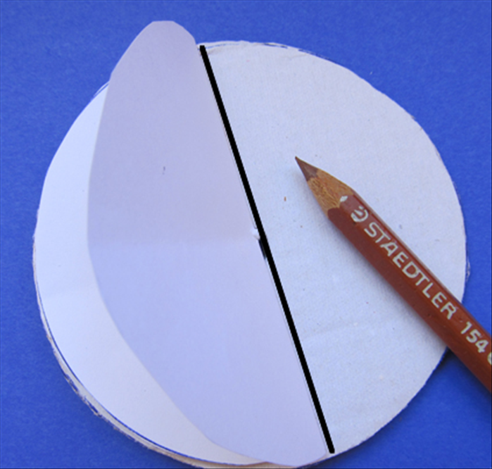 Fold the large paper circle in half.

Place it on top of the large cardboard circle and mark the line.

