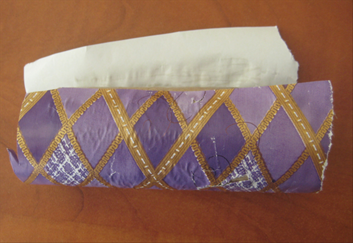 Roll up the toilet paper in the wrapping paper.
Spead glue on the underside of the wrapping paper and overlap the end .