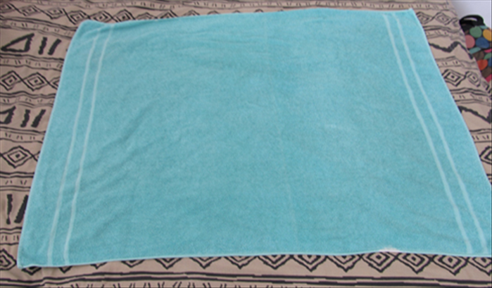 Open your bath towel so that the long ends are on top and bottom

Roll the left and right edges to meet at the center

