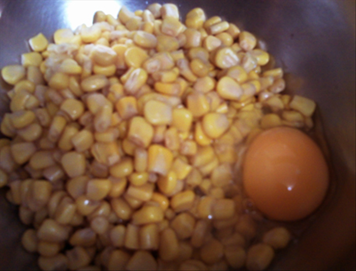 In large bowl mix together the egg and the drained corn